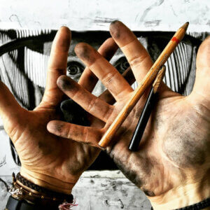 Manos del artista manchadas de grafito y carboncillo durante el proceso de dibujo de un retrato