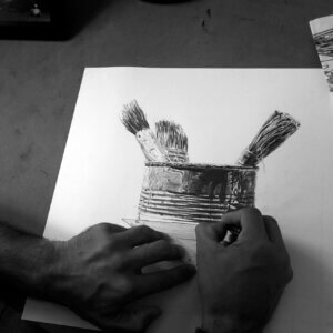 manos del artista dibujando una naturaleza muerta a grafito durante el proceso de trabajo