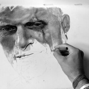 Mano del artista dibujando un retrato realista a grafito durante el proceso de trabajo