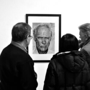Visitantes observando un retrato a grafito expuesto en una exposición en Sevilla