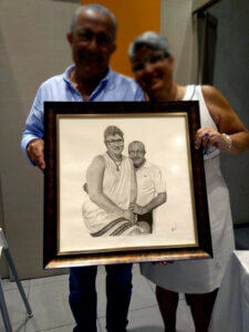 Retrato a lápiz y carboncillo de una pareja mayor sosteniendo un dibujo enmarcado